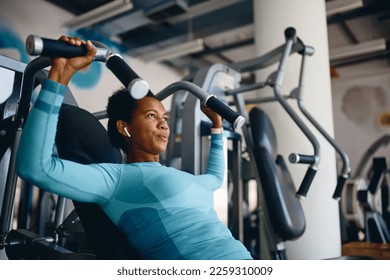 African American female athlete using exercise machine during strength training in a gym.
