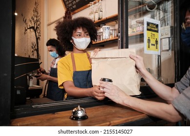 African American Female Barista With Face Mask Works In The Cafe With Social Distance, Takeaway Coffee For A Customer, New Normal Service Of Small Business Coffee Shop In COVID19 Quarantine Lifestyle.