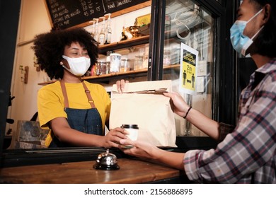 African American Female Barista With Face Mask Works In The Cafe With Social Distance, Takeaway Coffee For A Customer, New Normal Service Of Small Business Coffee Shop In COVID19 Quarantine Lifestyle.