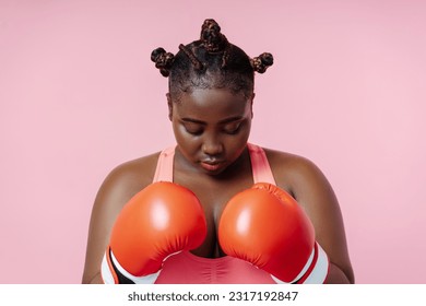 African american female boxer in red boxing gloves training isolated on pink background. Attractive woman doing sports, motivation, healthy lifestyle concept - Powered by Shutterstock