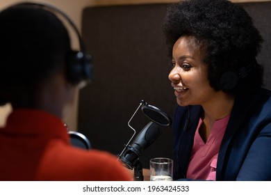 African American Female Business Colleagues In Discussion Speaking To Microphone And Smiling. Recording Podcast And Business A Modern Office.