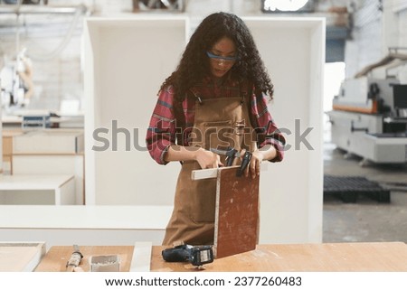 African American female carpenter working at wood factory. Female joiner works in wood factory