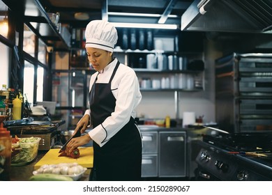 African American Female Chef Chopping Food While Preparing Meal At Restaurant Kitchen.