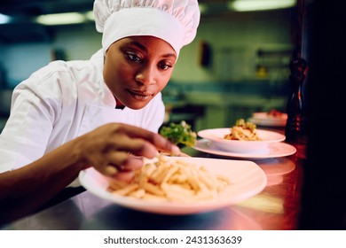 African American female chef decorating food plate cooking in the kitchen.  - Powered by Shutterstock