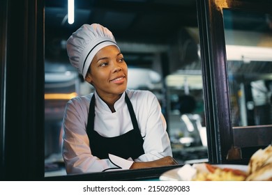 African American Female Chef Looking Through Window Of A Food Truck. 