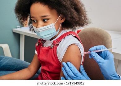 African American female child during vaccination in doctor's office. Vaccination of children while a global pandemic - Powered by Shutterstock