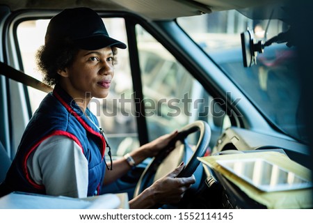 African American female courier driving delivery van in the city. 