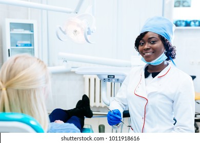 African American Female Dentist Treating Patient At Clinic. Dental Clinic Concept.