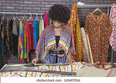 African American female designer measuring cloth at design studio
