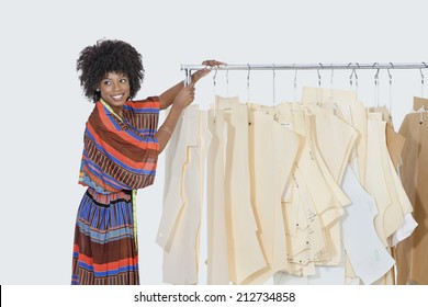 African American female designer with sewing patterns on clothes rack over gray background