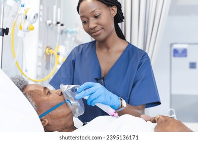 African american female doctor applying oxygen mask to senior female patient in hospital room. Medicine, healthcare and medical services, unaltered. - Powered by Shutterstock