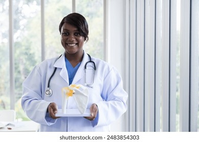 African American female doctor holding anatomy skeleton model in laboratory - Powered by Shutterstock