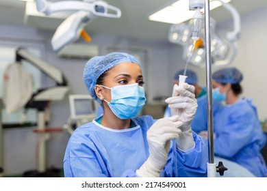 African american female Doctor in the operating room putting drugs through an IV - surgery concepts - Powered by Shutterstock