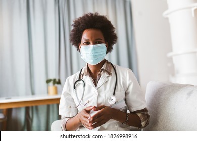 African american female doctor in protective facial mask looking at camera