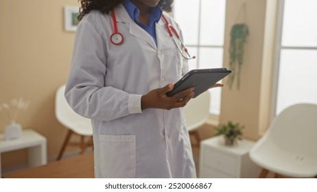 An african american female doctor reviews patient information on a tablet in a clinic's waiting room. - Powered by Shutterstock