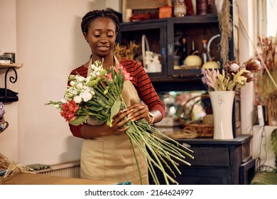 African American female florist making a bouquet of fresh flowers while working at flower shop. - Shutterstock ID 2164624997