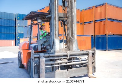 African American Female Foreman Is Driving A Forklift At Shipping Container Yard. Mixed Race Industrial Engineer Woman In Reflective Vest Drives Reach Stacker Truck At Import Export Cargo Terminal.