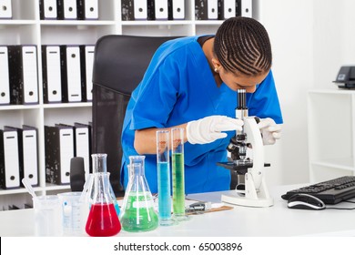 African American Female Lab Technician Looking Through Microscope In Lab