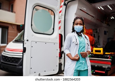 African American Female Paramedic In Face Protective Medical Mask Standing In Front Of Ambulance Car.