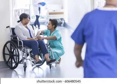 African American female patient in hospital wheelchair in corridor specialist care unit with medical staff - Powered by Shutterstock