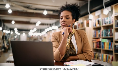 African American Female Professor Using Laptop While Doing A Research At University Library. 