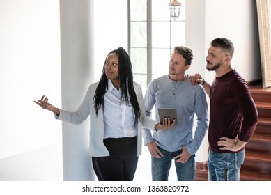 African American Female Real Estate Agent Showing Gay Couple Around New House