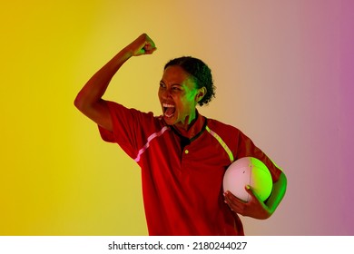 African american female rugby player raising hand with rugby ball over neon pink lighting. Sport, movement, training and active lifestyle concept. - Powered by Shutterstock