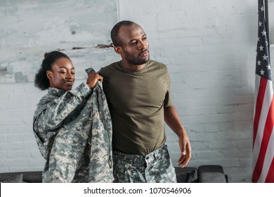 African American Female Soldier Helping Man To Get Dressed In Camouflage Clothes