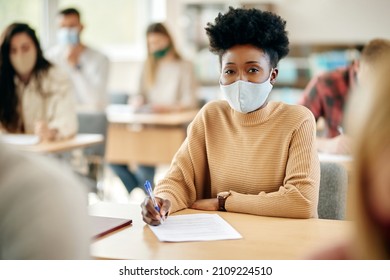 African American Female Student Having An Exam At The University And Wearing Face Mask Due To Coronavirus Pandemic.