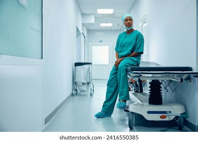 African American female surgeon sitting in hallway at medical clinic and looking away. Copy space.  - Powered by Shutterstock