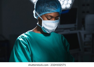 African american female surgeon wearing surgical gown and face mask in operating theatre. Hospital, surgery, medicine, healthcare and work, unaltered. - Powered by Shutterstock