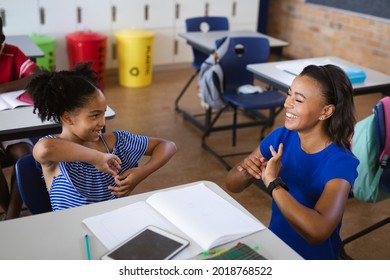 Afroamerikanische Lehrerin und ein Mädchen, das in der Grundschule spricht, signieren Sprache. Schulkonzept