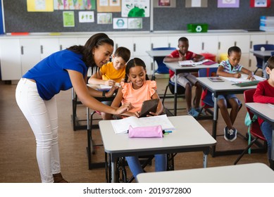 African american female teacher teaching disabled girl to use digital tablet at elementary school. school and education concept - Powered by Shutterstock