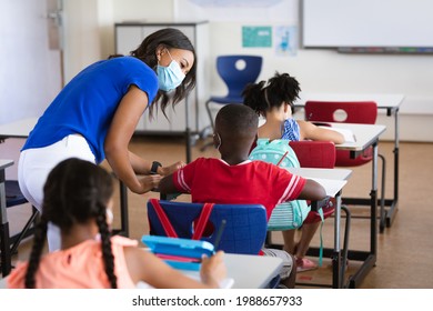 African American Female Teacher Wearing Face Mask Teaching African American Boy In Class At School. Education Back To School Health Safety During Covid19 Coronavirus Pandemic