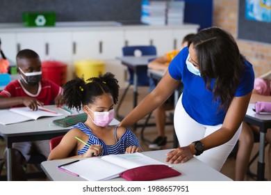 African American Female Teacher Wearing Face Mask Teaching African American Girl In Class At School. Education Back To School Health Safety During Covid19 Coronavirus Pandemic