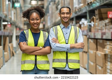 African American Female Worker And An Asian Male Colleague Wearing Safety Uniforms At Work, Arms Crossed, Proud And Happy To Serve Customers In Wholesale Warehouses.