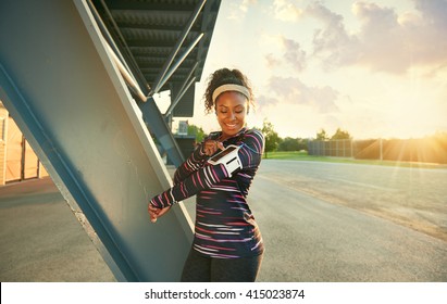 African American Fit Woman Choosing Music From An App For Running At Sunset 