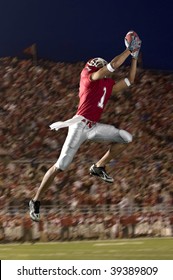 African American Football Wide Receiver Leaping Up To Catch A Football. Vertically Framed Shot.