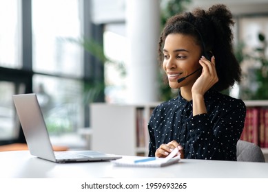African American friendly young woman with headset, call center worker, consultant, business person, looks at the laptop screen, talking with colleagues or clients by video call, conducts consultation - Shutterstock ID 1959693265