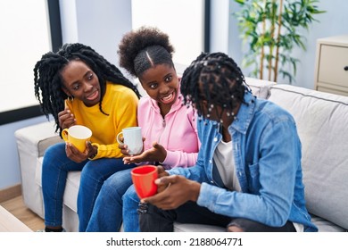 African American Friends Drinking Coffee Sitting On Sofa At Home