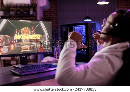 African american gamer happy about winning online multiplayer matchup against other players. Man seeing winner message on gaming PC computer screen in rgb lights living room