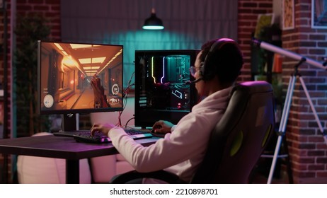 African American Gamer Having Intense Experience Streaming Online First Person Shooter Game On Pc Station At Home. Man Playing Intense Action Game In Tournament Talking With Team Using Gaming Headset.