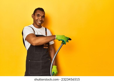 African American gardener with plant and hose, yellow studio setting. - Powered by Shutterstock