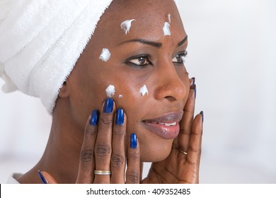 African American girl applying facial skincare product  