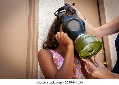 African American Girl Being Fitted For Gas Mask At An Apartment Complex. Image Can Be Used For Coronavirus,Covid-19,Pandemic,air Pollution, Second Hand Smoke ,or Asthma