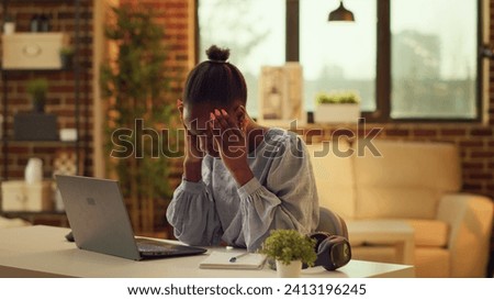 African american girl being in pain at home, suffering from extreme headache while trying to solve daily responsibilities. Woman freelancer stressed about migraine, being under pressure.