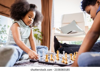 African American Girl And Boy Playing Chess On The Floor In The Living Room At Home