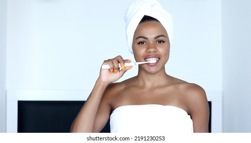 African American Girl Brushing Teeth With Toothbrush Looking In Mirror In Bathroom. Dental Care Concept.