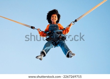 Image, Stock Photo Bungee jumping at trampoline. Little girl bouncing on bungee jumping in amusement park on summer vacations