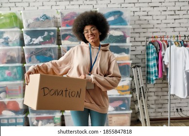 African American Girl Holding Donation Box And Smiling At Camera. Young Volunteer Working At Charity Shop